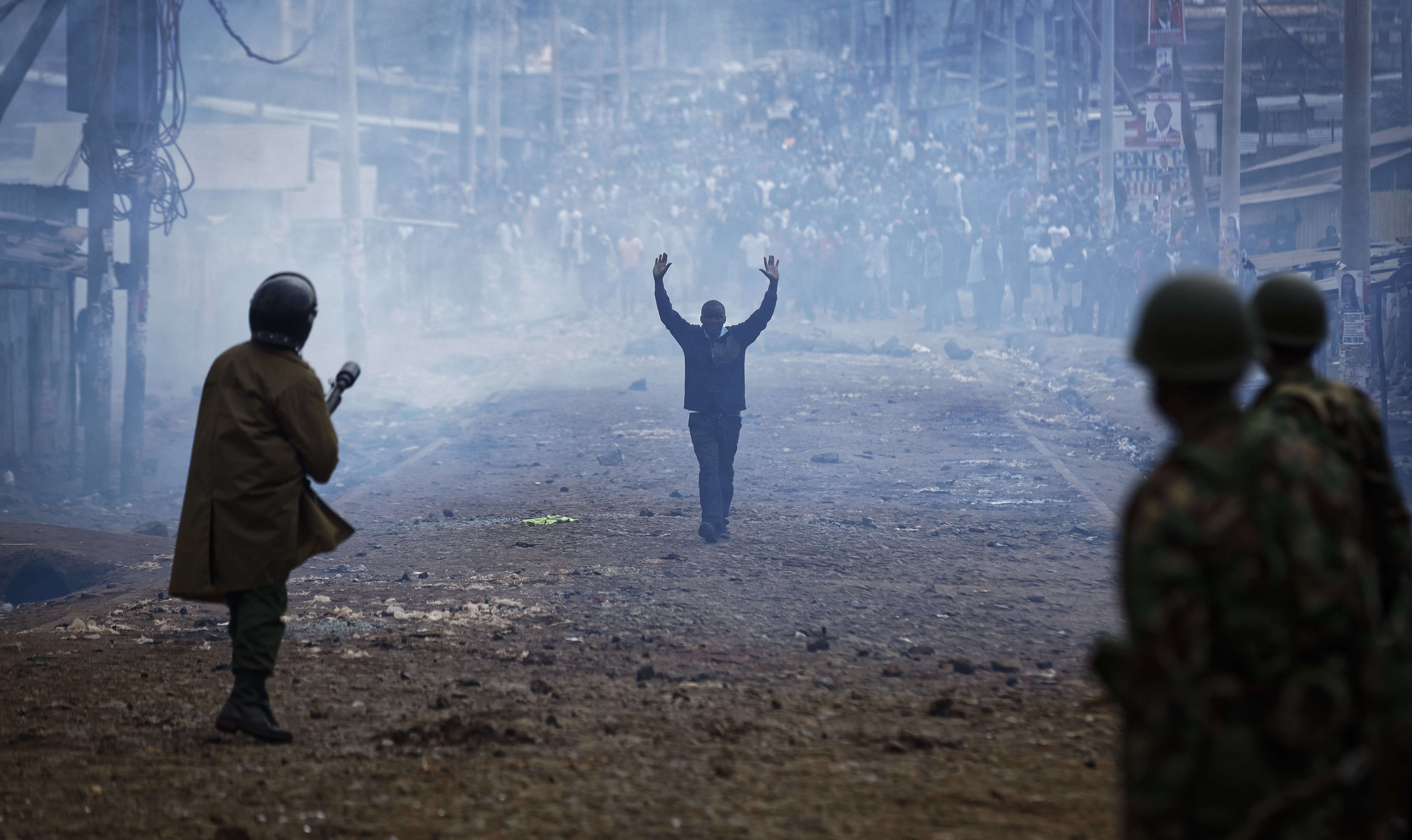 Les mains en l’air, un homme marche à travers un nuage de gaz lacrymogène vers la police antiémeute affrontant les jets de pierres de manifestants dans le bidonville de Kawangware, à Nairobi.  Vingt-quatre personnes ont été tuées par la police en marge des élections du 8 août. Dès l’annonce des résultats du scrutin présidentiel par la commission électorale (IEBC), des émeutes ont éclaté dans les fiefs de l’opposition au chef de l’Etat du Kenya réélu, Uhuru Kenyatta.
