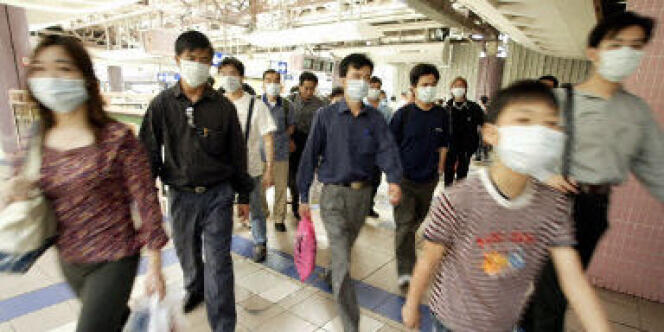 Des personnes portant des masques pour se protéger du syndrome respiratoire aigu sévère (SRAS) à Hongkong, le 22 avril 2003.