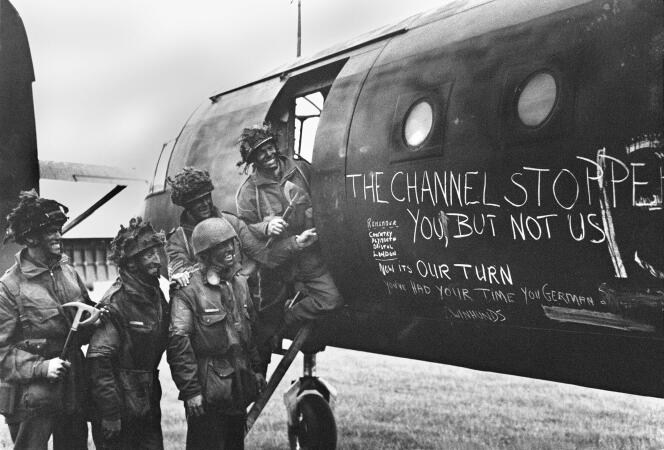 Des soldats britanniques devant leur avion recouvert de slogans, en juin 1944.