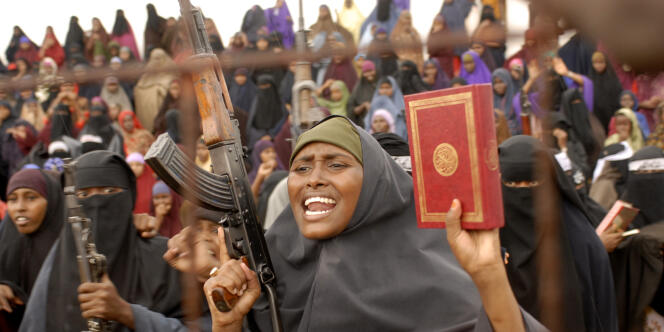Des femmes brandissent le Coran et des armes distribuées par des miliciens de l'Union des tribunaux islamiques, le 8 décembre 2006, dans un stade de Mogadiscio. 