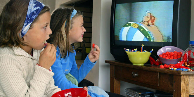 Deux petites filles regardent la télévision en mangeant des sucreries, le 08 octobre 2003 à Rennes.