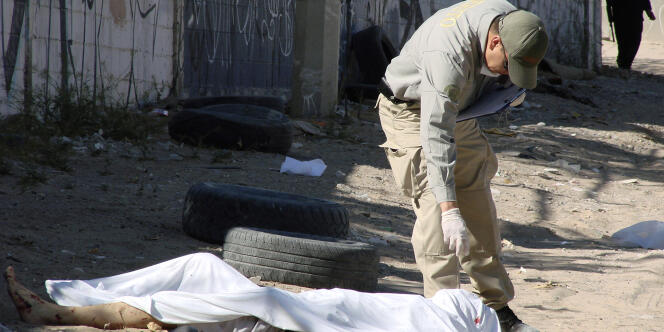 Un policier inspecte le corps d'un homme qui a a été tué par des inconnus, à Ciudad Juarez, au Mexique, le 10 avril 2009.