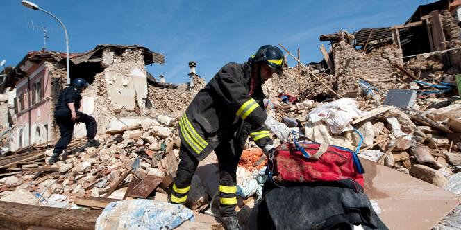 Des pompiers fouillent dans les ruines des bâtiments totalement détruits par le séisme qui a touché la région de l'Aquila, dans la nuit du 6 avril 2009.