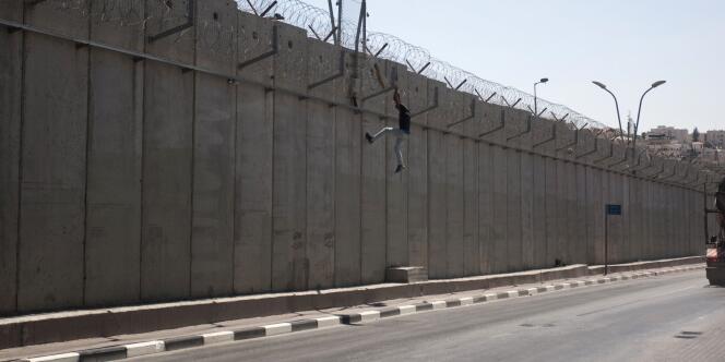 Un homme escalade le mur qui sépare la Cisjordanie de Jérusalem.
