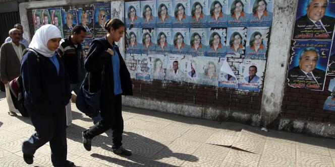 Des écolières passent devant des affiches électorales présentant une candidate aux élections générales, au Caire.
