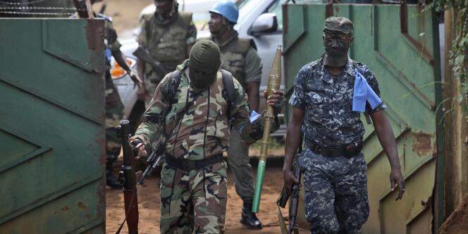 Des membres des Forces nouvelles sortent lourdement armés de l'hôtel qui sert de quartier général à Alassane Ouattara, jeudi 16 décembre.