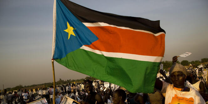 Des jeunes brandissent le drapeau du Soudan du Sud lors d'un meeting électoral, à l'université de Juba. 