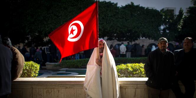 Un manifestant brandit le drapeau tunisien, samedi 22 janvier, à Tunis.