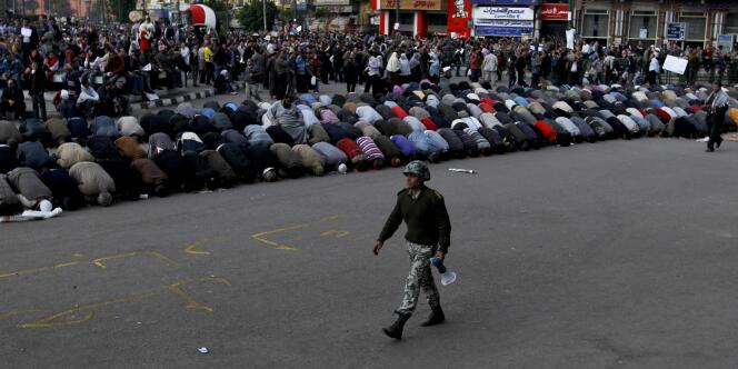 Un soldat égyptien passant devant les manifestants du Caire sur la place Tahrir, pendant leur prière, le 30 janvier.