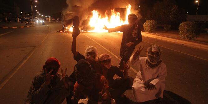 Des manifestants devant un véhicule en flammes à Sohar, le 27 février 2011.