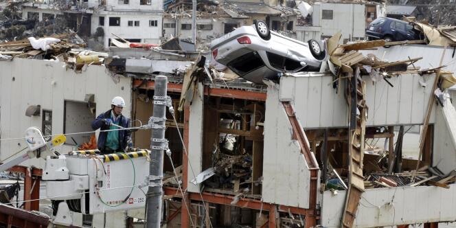 Des ouvriers tentent de réparer des lignes de courant dévastées par le séisme et le tsunami du 11 mars, à Onagawa, dans la préfecture de Miyagi.