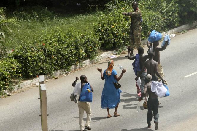 Des civils, bras en l'air, devant un soldat pro-Gbagbo, dimanche à Abidjan.