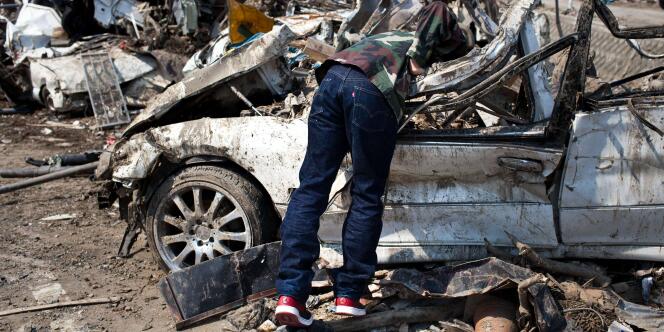 Un survivant du tsunami du 11 mars fouille un véhicule anéanti à Minamisanriku, le 13 avril 2011.