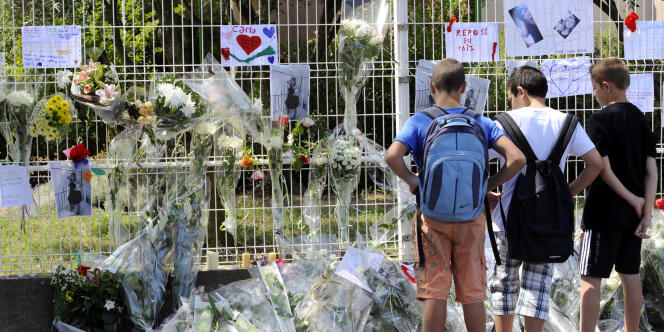 Des collégiens se recueillent devant des fleurs et messages déposés à l'entrée du collège Voltaire à Florensac, le 21 juin. 