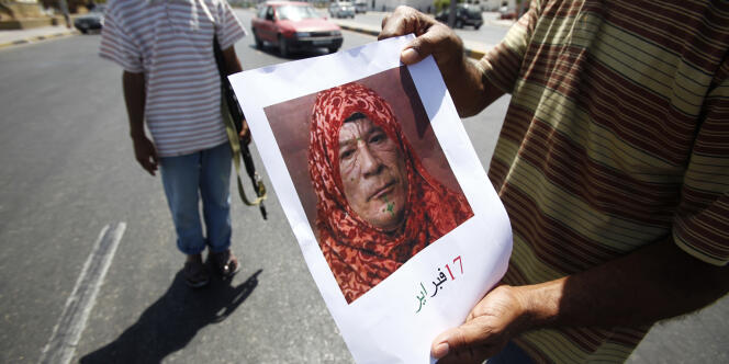 Un combattant rebelle présente un montage photo montrant le colonel Kadhafi déguisé en femme berbère, lundi 29 août, à Tripoli. 