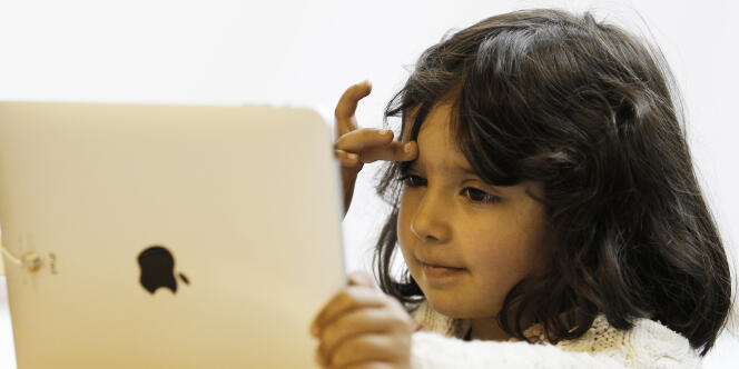 Une petite fille utilise une tablette Apple. 
