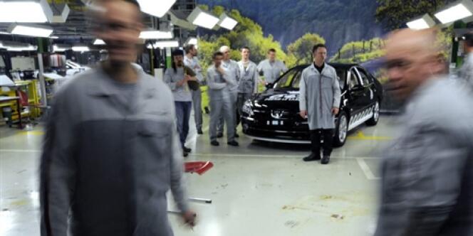 Des ouvriers de l'usine PSA de Sochaux sont rassemblés autour de la dernière Peugeot 607 produite ce jour dans l'usine, le 4 mars 2009. 