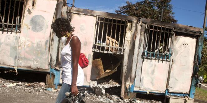 Une femme passe devant un centre social brûlé de Saint-Denis le 23 février, après la deuxième nuit d'émeutes contre la vie chère à la Réunion
