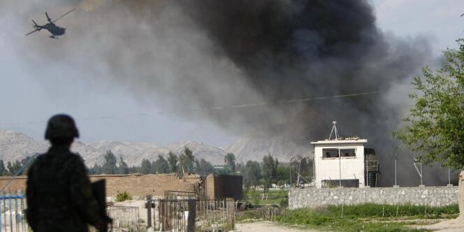 Un soldat afghan en faction près d'un site attaqué par les talibans, dimanche 15 avril, alors qu'un hélicoptère de l'OTAN est en approche.