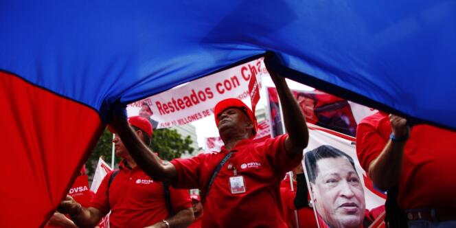 Des salariés de la compagnie nationale pétrolière brandissent des portraits d'Hugo Chavez, lors du défilé du 1er-Mai, dans les rues de Caracas.