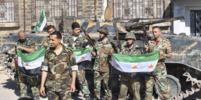 Des militaires syriens faisant défection posent avec un drapeau de l'opposition, le 12 mai, dans la province de Homs.