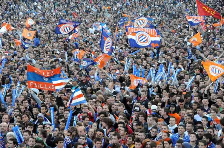 Montpellier's fans wave flags as they wait in front of a giant screen to watch the broadcast French L1 football match Montpellier vs Auxerre on May 20, 2012 at the place de la Comedie in Montpellier, southern France. To celebrate like champions, Montpellier team still requires a point at relegated Auxerre to claim the first Ligue 1 title in their history.    AFP PHOTO / PASCAL GUYOT