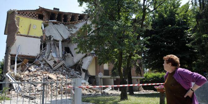 Une femme passe devant un immeuble effondré à Cavazzo, dans le nord de l'Italie, le mardi 29 mai 2012.