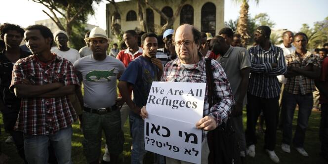Un manifestant israélien se tient aux côtés d'immigrés africains en signe de solidarité et tient une pancarte sur laquelle est inscrit 