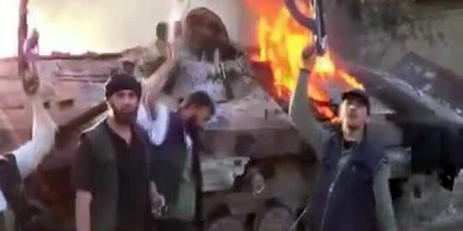Capture d'écran montrant des rebelles à proximité d'un blindé incendié, dans la banlieue de Damas.