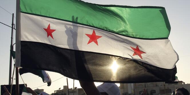 Des manifestants brandissent le drapeau de l'opposition syrienne et chantent des slogans à la gloire du pilote déserteur syrien devant l'ambassade de Syrie à Amman, en Jordanie.
