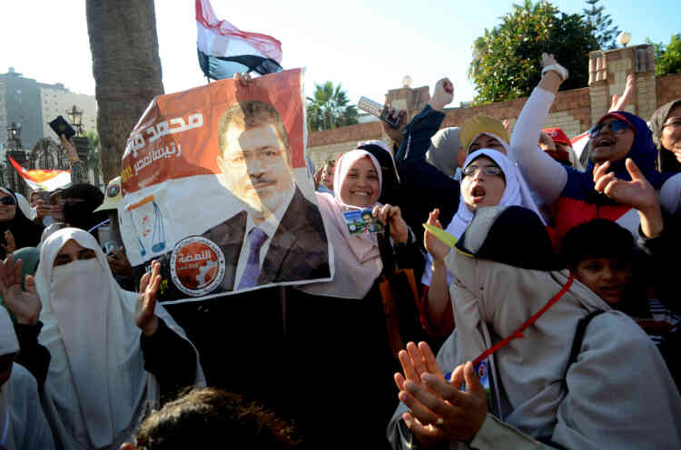 Female supporters of Egypt's Muslim Brotherhood candidate Mohamed Morsi (portrait) celebrate, in the northern coastal city of Alexandria, after Egypt's elections presidential committee declared Morsi as the winner in a divisive run-off with ex-premier Ahmed Shafiq on June 24, 2012. Morsi has vowed to uphold the goals of the revolution that ousted president Hosni Mubarak last year and to share power with other parties. AFP PHOTO / STR