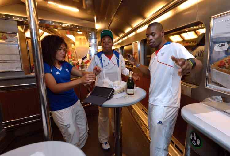 French cyclist Gregory Bauge (R) and Taekwondo Anne-Caroline Graffe (L) drink a glass of champagne in the train going back to Paris after the London 2012 Olympic Games on August 13, 2012 in London. France finished the London Olympics Games with 34 medals including 11 gold, 11 silver and 12 bronze, and placed on the seventh position in the all nations ranking. AFP PHOTO / ERIC FEFERBERG