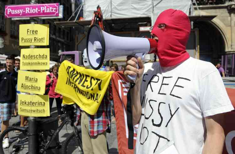 A masked activist of of the human rights organization Amnesty International shouts slogans next to the pasted street sign of the Marienplatz place with Pussy-Riot-Platz (Platz is German for place) in Munich, southern Germany, Friday, Aug. 17, 2012, during a demonstration for the Russian punk band Pussy Riot. Three members of Russian punk group Pussy Riot were jailed in March and charged with hooliganism motivated by religious hatred after their punk performance against President Putin in Moscow’s main cathedral. A judge found three members of the provocative punk band Pussy Riot guilty of hooliganism on Friday, in a case that has drawn widespread international condemnation as an emblem of Russia's intolerance of dissent. (AP Photo/dapd, Lennart Preiss)