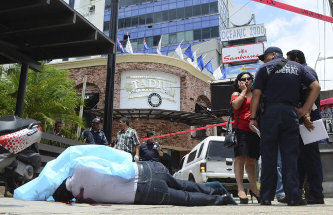 Le corps d’un homme tué par balles, entouré par la police fédérale, sur l’avenue touristique 
La Costera, qui longe la baie d’Acapulco, le 17 août .