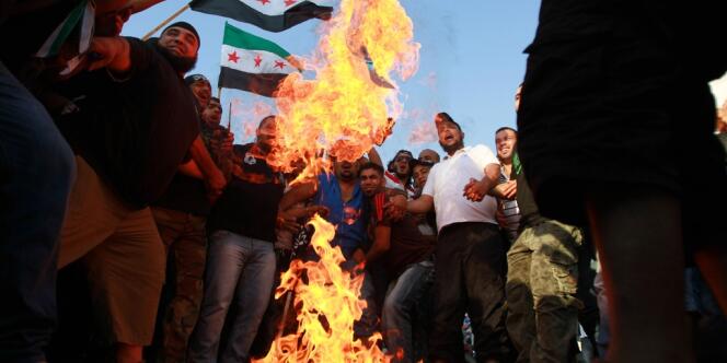 Des manifestants brûlent des drapeaux américains et israéliens pour protester contre le film islamophobe, et brandissent des drapeaux syriens en solidarité avec la rébellion dans le pays voisin, le 16 septembre à Tripoli, au Liban.   