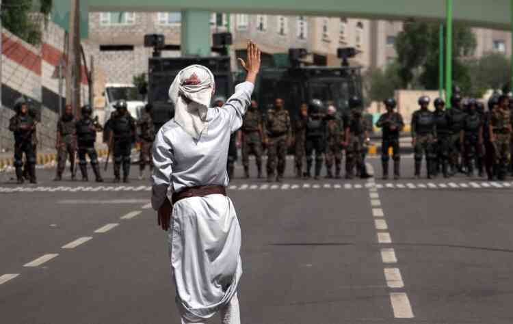 A Yemeni protester gestures before the riot policemen during a demonstration on a road leading to the US embassy in Sanaa on September 21, 2012 to protest against a US-made film mocking Islam as security forces prevented them from reaching Washington's heavily guarded embassy. The protesters demanded "the departure of the US ambassador and foreign forces in Yemen," in reference to 50 Marines who were dispatched last week to protect the embassy. AFP PHOTO/MOHAMMED HUWAIS