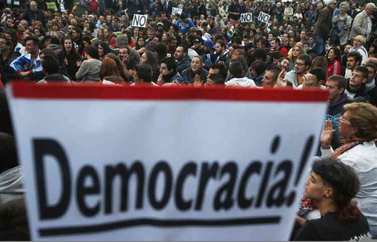 Protesters take part in a demonstration outside Madrid's Parliament September 26, 2012. Violent protests in Madrid and growing talk of secession in Catalonia are piling pressure on Spanish Prime Minister Mariano Rajoy as he moves closer to asking Europe for rescue money. The placard reads "Democracy!".  REUTERS/Susana Vera (SPAIN - Tags: CIVIL UNREST POLITICS)