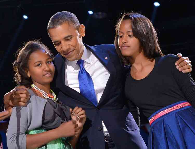 US President Barack Obama hugs his daughters Sasha (L) and Malia (R) on election night November 6, 2012 in Chicago, Illinois. President Barack Obama swept to re-election Tuesday, forging history again by transcending a slow economic recovery and the high unemployment which haunted his first term to beat Republican Mitt Romney. AFP PHOTO/Jewel Samad