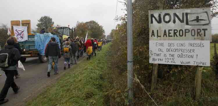 People walk near a sign which reads, "Airport No" as they take part in a demonstration against plans to construct a new airport in Notre-Dame-des-Landes, western France, November 17, 2012. The new airport, some 30kms (19 miles) from Nantes, is scheduled to be constructed for 2017.  REUTERS/Stephane Mahe (FRANCE  - Tags: TRANSPORT CIVIL UNREST POLITICS)
