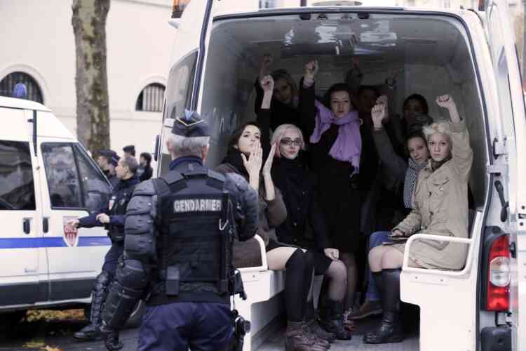 Topless activists of the Ukrainian women movement Femen raise fist in a van after an action against the fierce opposition from the Roman Catholic Church to authorise gay marriage on November 18, 2012 in Paris.   AFP PHOTO KENZO TRIBOUILLARD