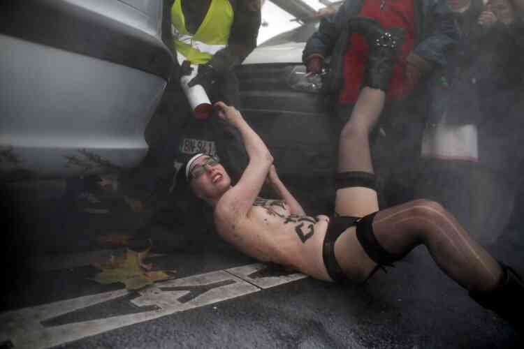 TOPSHOTS
A topless activist of the Ukrainian women movement Femen is evacuated by a security man of anti same sex-marriage people during an action against the fierce opposition from the Roman Catholic Church to authorise gay marriage on November 18, 2012 in Paris.   AFP PHOTO KENZO TRIBOUILLARD