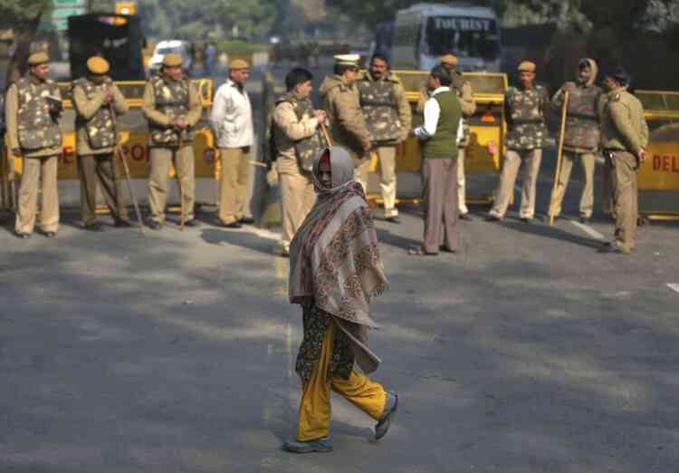 A woman walks past police officers standing guard in front of a closed road leading to the India Gate in New Delhi December 29, 2012. An Indian woman whose gang rape in New Delhi triggered violent protests died of her injuries on Saturday in a Singapore hospital, bringing a security lockdown in Delhi and recognition from India's prime minister that social change is needed. The India Gate has been the epicenter of previous related protests. REUTERS/Ahmad Masood (INDIA - Tags: CIVIL UNREST CRIME LAW)