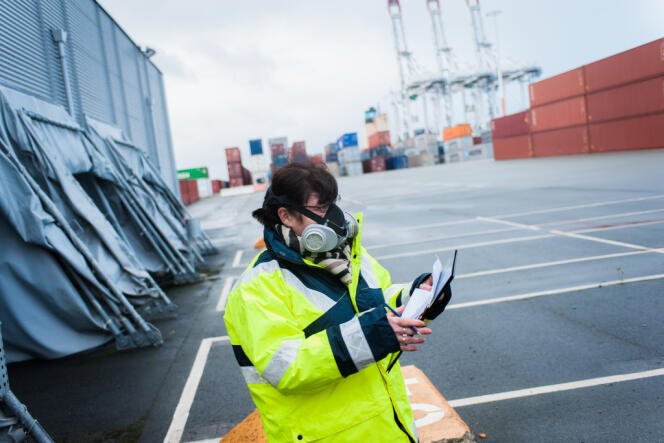 Une douanière enfile un masque à gaz avant de procéder à l'inspection d'un conteneur entreposé sur un quai du port du Havre, le 27 décembre.