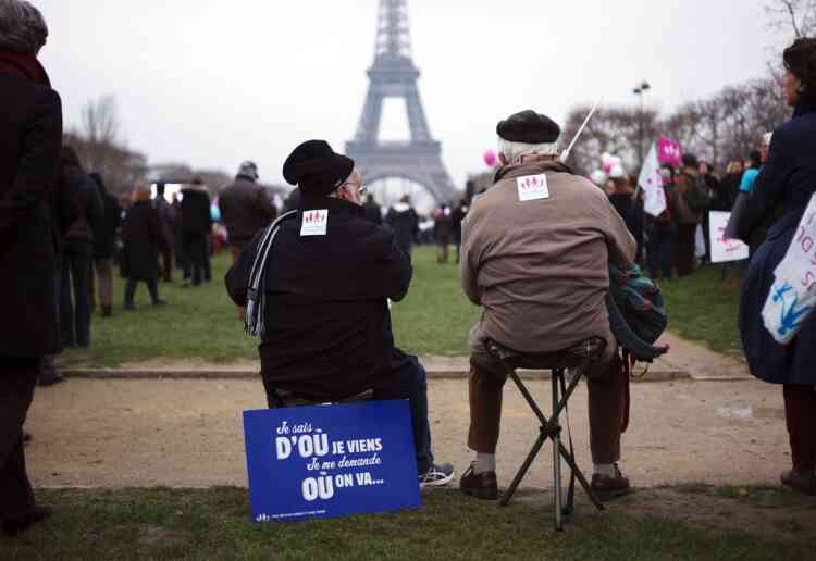 Men sit near a placard reading "I know where I came, I don't know where we go" during a protest against same-sex marriage on the Champs-de-Mars in Paris, on January 13, 2013. Tens of thousands march in Paris on January 13 to denounce government plans to legalise same-sex marriage and adoption which have angered many Catholics and Muslims, France's two main faiths, as well as the right-wing opposition. The French parliament is to debate the bill -- one of the key electoral pledges of Socialist President -- at the end of this month. AFP PHOTO / LIONEL BONAVENTURE