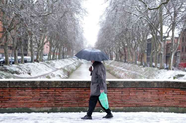 A man walks by the snow covered banks of the Canal de Brienne, on January 20, 2013 in Toulouse southern France, after heavy snow falls.    AFP PHOTO PHOTO / PASCAL PAVANI