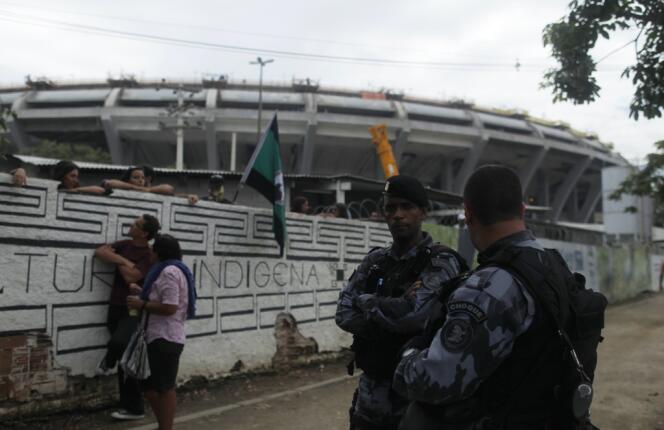 Des policiers antiémeutes montent la garde, le 13 janvier, devant la Maison des Indiens de Rio promise à la démolition. En arrière-plan, le stade Maracana, en pleine rénovation pour la Coupe du monde de football 2014.