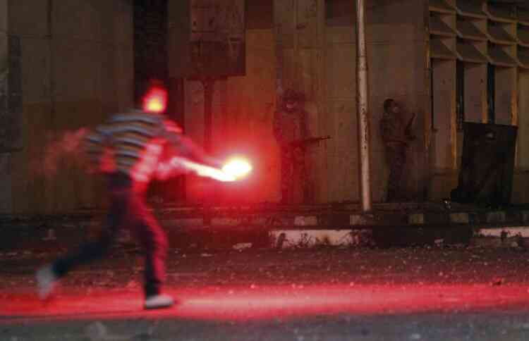 A protester throws a flare as an army soldier (C) prepares to fire towards riot police as the latter tries to stop clashes between protesters who oppose Egyptian President Mohamed Mursi and riot police, in front of Security Directorate of Port Said after protesters started to set fire to it in Port Said city, 170 km (106 miles) northeast of Cairo March 4, 2013. Protesters hurled petrol bombs and stones at police officers who responded by firing teargas in Egypt's Port Said on Monday, a day after deadly demonstrations in the Suez Canal city. REUTERS/Amr Abdallah Dalsh (EGYPT - Tags: POLITICS CIVIL UNREST)