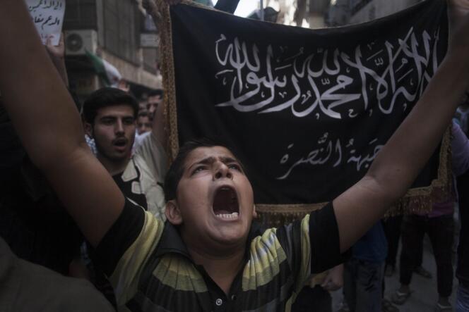 Un enfant syrien chante des slogans contre le régime, devant un drapeau du Front Al-Nousra, dans un quartier d'Alep, le 21 septembre 2012.
