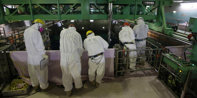 Protégés par une combinaison et un masque, des travailleurs tentent de décontaminer un bassin de rétention de fuel dans la centrale de Fukushima, en mars. 