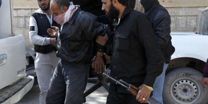 Des membres du groupe djihadiste Al-Nosra détiennent un prisonnier dans la province de Rakka, dans l'est de la Syrie, le 14 mars 2013.